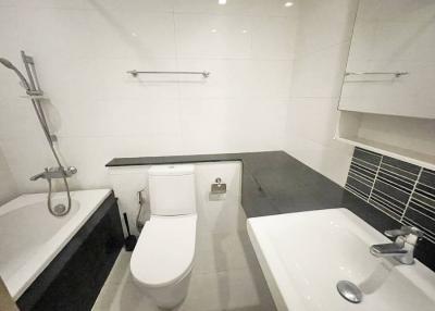 Modern white bathroom with toilet, sink, and shower