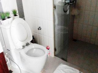 Modern bathroom interior with white ceramic fixtures and glass shower partition