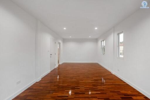 Spacious empty bedroom with polished hardwood floor and bright white walls