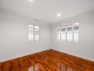 Spacious bedroom with polished hardwood floor and natural light