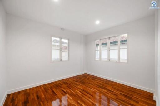 Spacious bedroom with polished hardwood floor and natural light