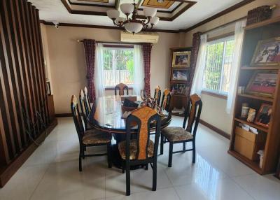Elegant dining room with a polished wooden dining table and chairs, ornate ceiling design, and ample natural light