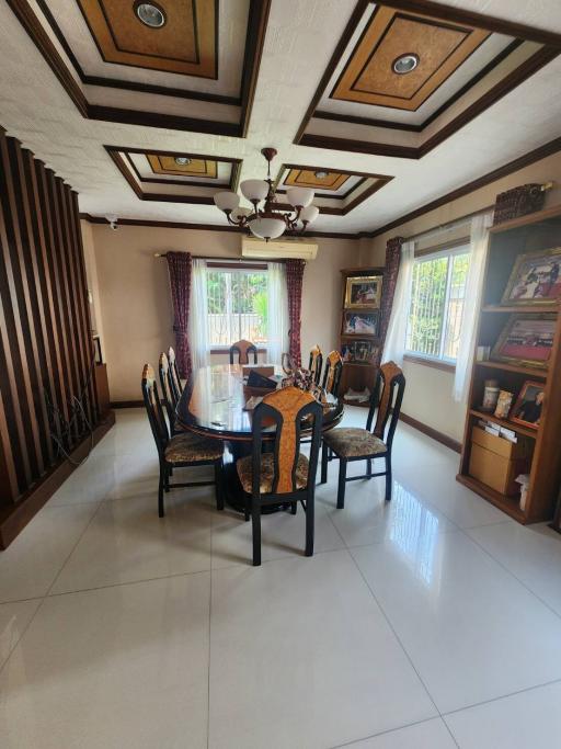 Elegant dining room with a polished wooden dining table and chairs, ornate ceiling design, and ample natural light