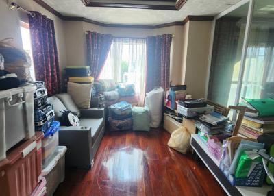 Cluttered living room with natural light and hardwood floors