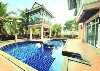 Private swimming pool with adjoining house and palm trees