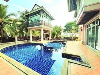 Private swimming pool with adjoining house and palm trees