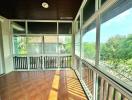 Spacious balcony with wooden ceiling and panoramic windows overlooking greenery