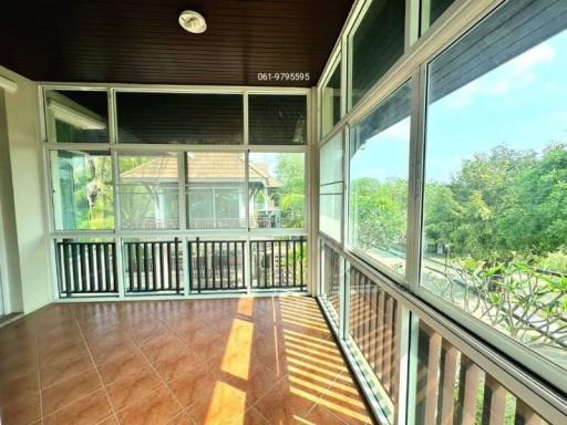 Spacious balcony with wooden ceiling and panoramic windows overlooking greenery