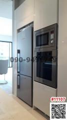 Modern kitchen with stainless steel appliances, including a refrigerator and a built-in microwave