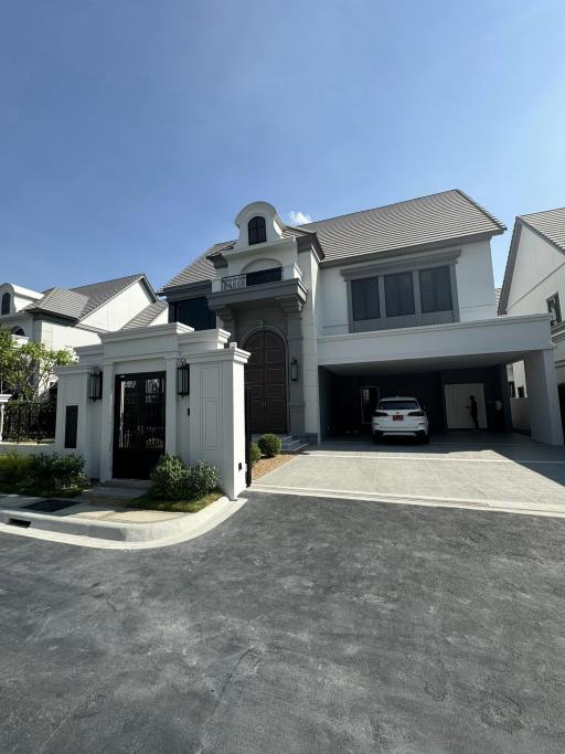 Elegant two-story house with a large driveway and garage under a clear blue sky