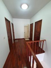 Spacious hallway with hardwood flooring and multiple wooden doors
