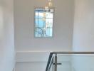 Bright staircase area with modern chandelier and glass railing