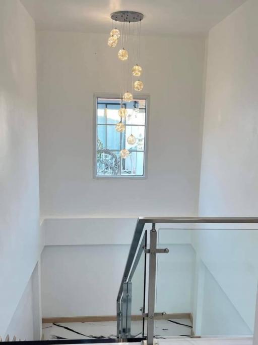 Bright staircase area with modern chandelier and glass railing