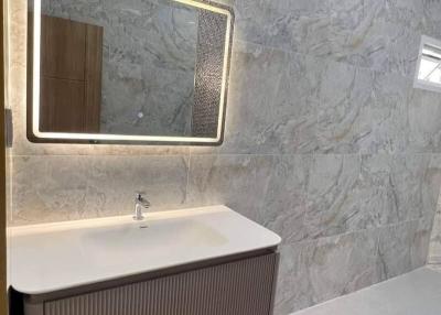 Modern bathroom interior with illuminated mirror and marble walls