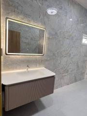 Modern bathroom interior with illuminated mirror and marble walls