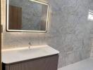 Modern bathroom interior with illuminated mirror and marble walls