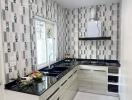 Modern kitchen with black countertops and patterned backsplash