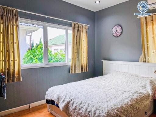 Cozy bedroom with a large window and wooden flooring