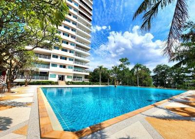 Swimming pool with a modern high-rise apartment building in the background on a sunny day