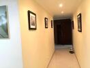 Bright and spacious hallway with tiled flooring and decorative wall frames leading to a wooden door