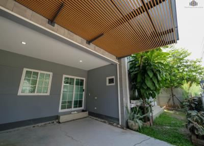 Modern house exterior with wooden slats, large windows, and a spacious patio