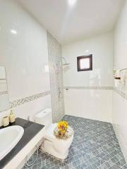 Modern bathroom with white and grey tiles, wall-mounted sink, and glass shower partition