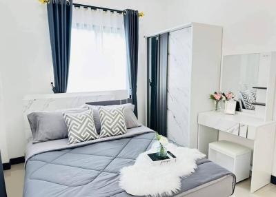 Modern bedroom with a stylish bed, window curtains, and an adjoining vanity area