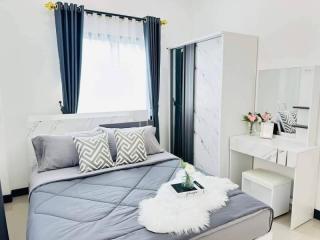 Modern bedroom with a stylish bed, window curtains, and an adjoining vanity area