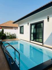 Outdoor swimming pool with clear blue water adjacent to a white residential building