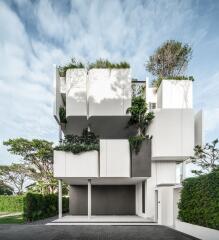 Modern multi-level residential building with lush greenery and a spacious garage entrance