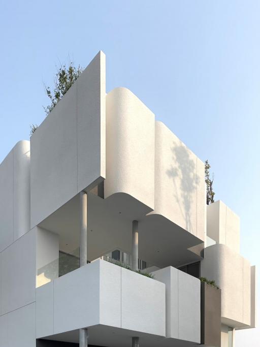 Modern architectural design of a multi-level residential building with balconies and plant decor