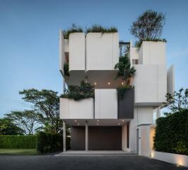 Modern multi-story residential building with architectural greenery at dusk