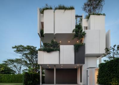 Modern multi-story residential building with architectural greenery at dusk