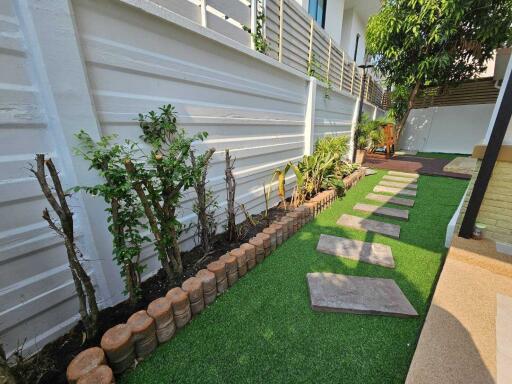 Well-maintained garden path with artificial grass and decorative plants