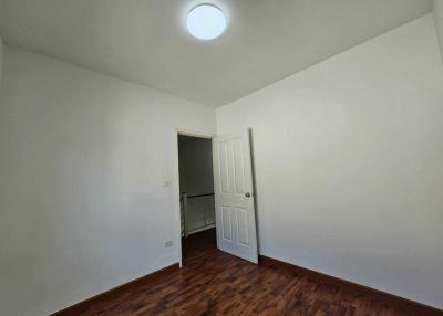 Empty bedroom with white walls and wooden floor