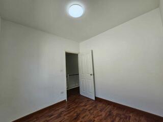 Empty bedroom with white walls and wooden floor