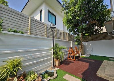 Suburban home backyard with a small lawn, privacy fence, and children