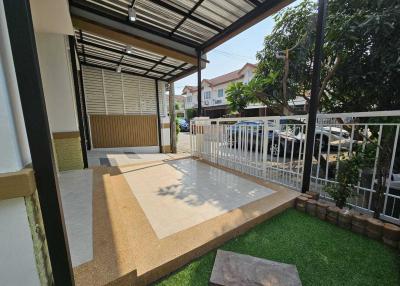 Spacious covered patio area with artificial grass and parking space