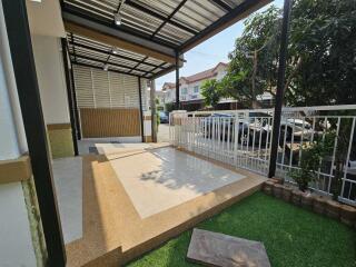 Spacious covered patio area with artificial grass and parking space