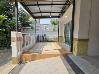 Spacious covered patio area with tiled flooring and a modern fence