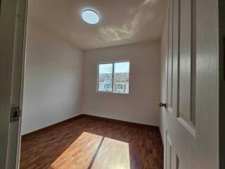 Empty bedroom with hardwood floors and natural light