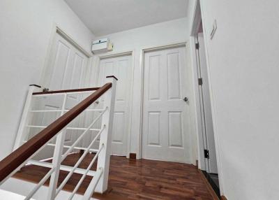 Spacious well-lit hallway with hardwood floors and white doors