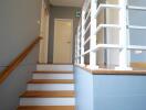 Modern wooden staircase with white balustrade in a well-lit interior