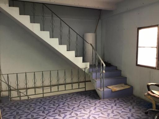 Interior view of a building with stairs, patterned flooring, and a chair