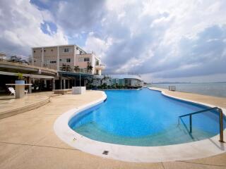 Spacious outdoor pool with a view of the waterfront adjacent to a modern residential building