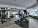 Modern home gym with cardio equipment and weights overlooking a pool