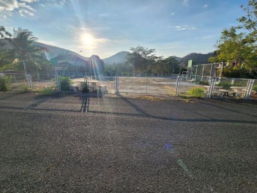 Sun setting over a paved area with fencing and mountain views