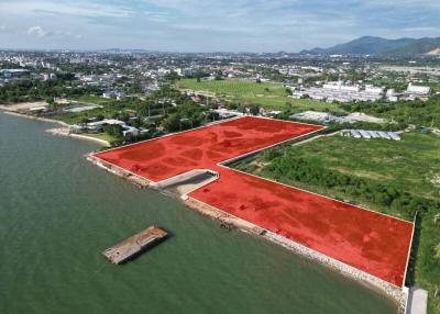 Aerial view of waterfront property with red soil and surrounding greenery under a clear sky