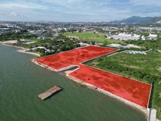 Aerial view of waterfront property with red soil and surrounding greenery under a clear sky