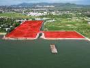 Aerial view of large waterfront area with red soil